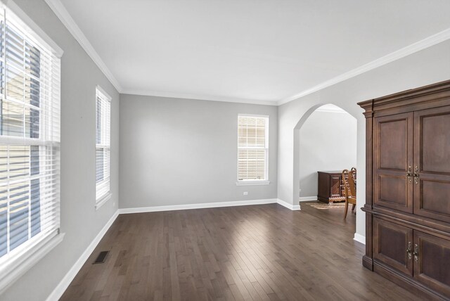 spare room with visible vents, arched walkways, plenty of natural light, and dark wood-style floors