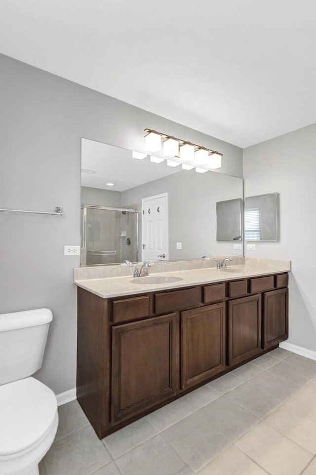 full bath featuring a shower stall, baseboards, toilet, double vanity, and a sink