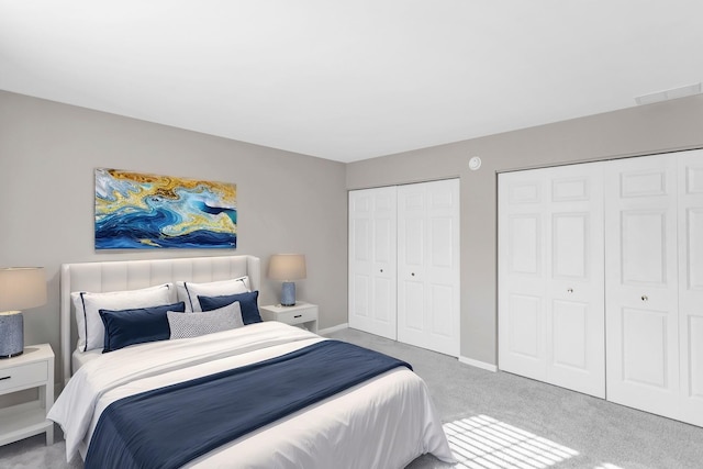 bedroom featuring baseboards, two closets, and carpet floors