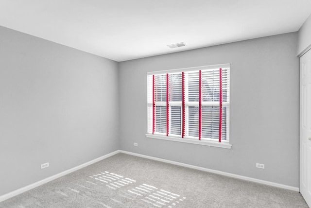 empty room with carpet, visible vents, and baseboards