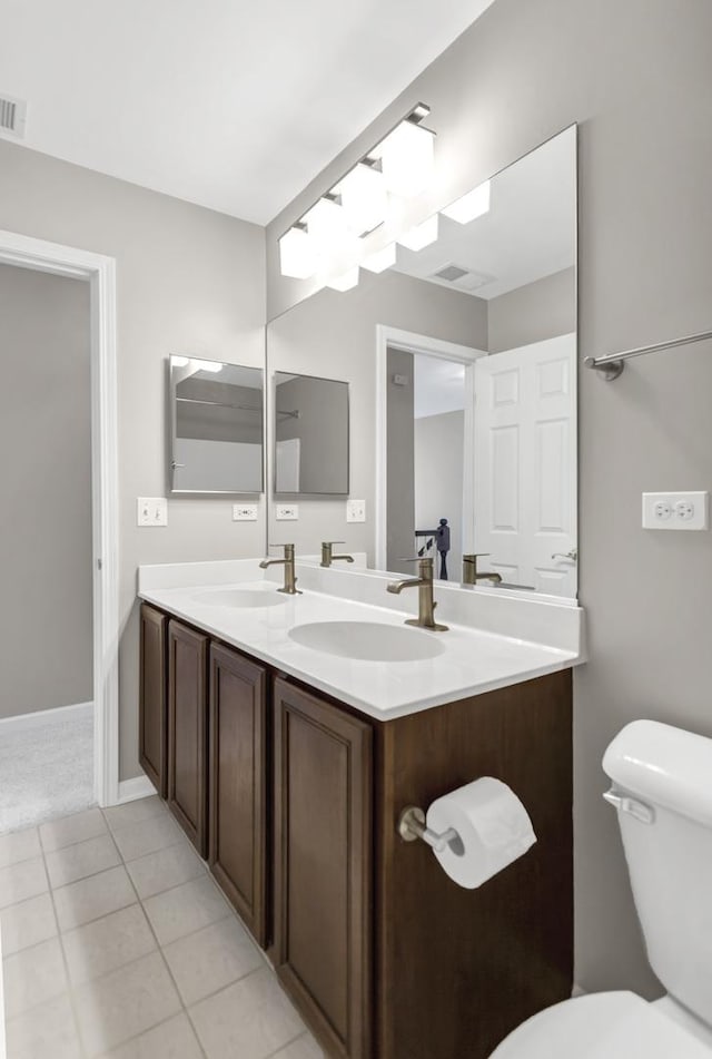 bathroom with double vanity, toilet, tile patterned floors, and a sink