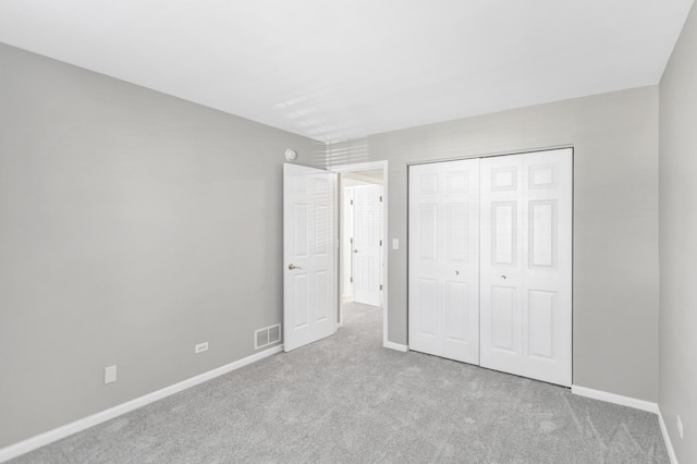 unfurnished bedroom with visible vents, baseboards, a closet, and carpet flooring