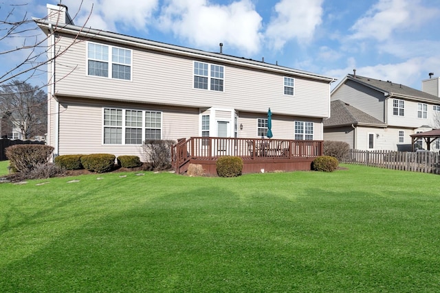 rear view of house featuring a yard, a deck, a chimney, and fence