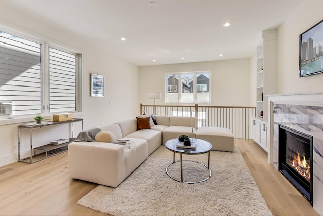 living area featuring recessed lighting, light wood-type flooring, and a fireplace