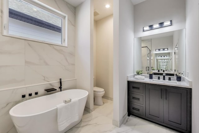 bathroom featuring a freestanding tub, toilet, marble finish floor, and vanity