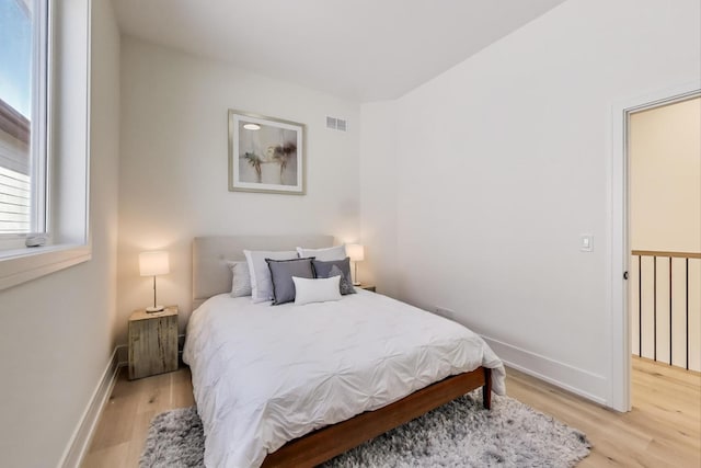 bedroom featuring baseboards, visible vents, and light wood finished floors