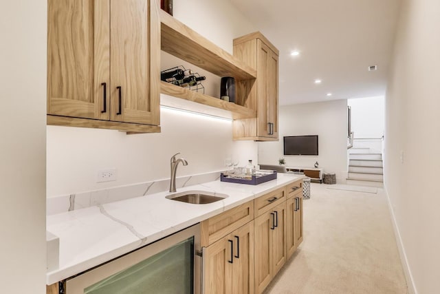 kitchen with beverage cooler, light brown cabinets, a sink, open shelves, and light stone countertops