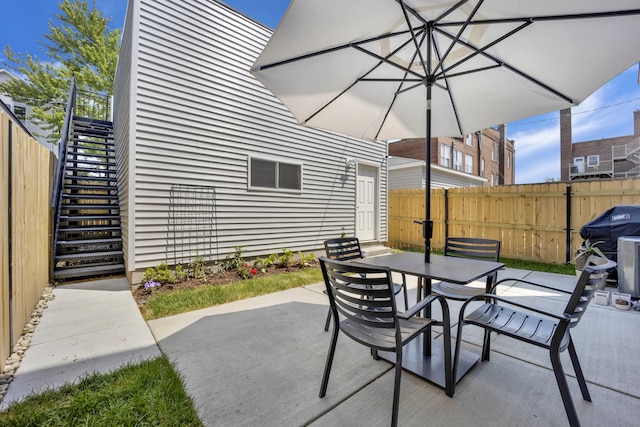 view of patio / terrace with stairway, outdoor dining space, and fence