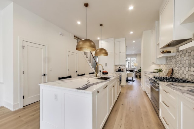 kitchen featuring white cabinetry, stainless steel stove, custom range hood, and a sink