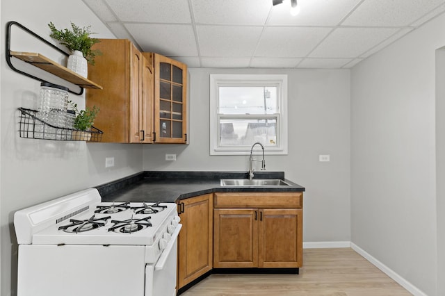 kitchen featuring brown cabinets, a sink, open shelves, gas range gas stove, and dark countertops