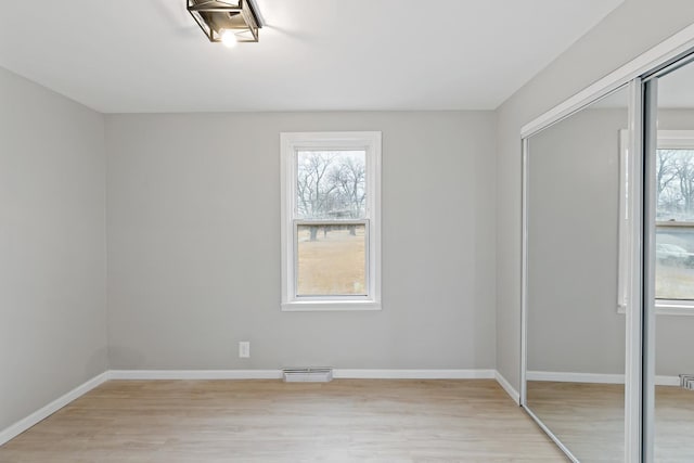 unfurnished bedroom featuring a closet, baseboards, visible vents, and light wood-style flooring