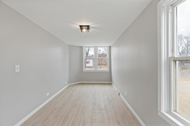 unfurnished room featuring light wood-type flooring, baseboards, and visible vents