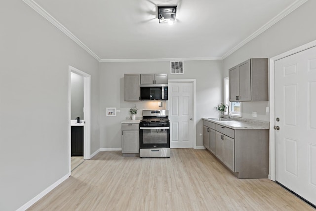 kitchen with visible vents, light wood-type flooring, gray cabinetry, a sink, and appliances with stainless steel finishes