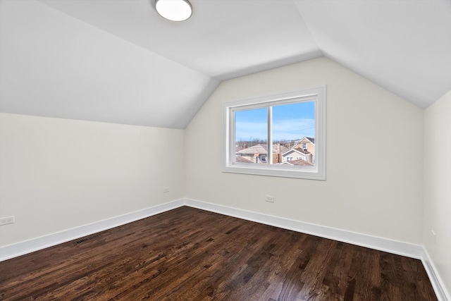 bonus room featuring visible vents, baseboards, dark wood-type flooring, and vaulted ceiling