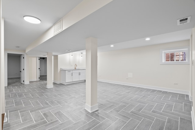 below grade area featuring a sink, visible vents, baseboards, and recessed lighting