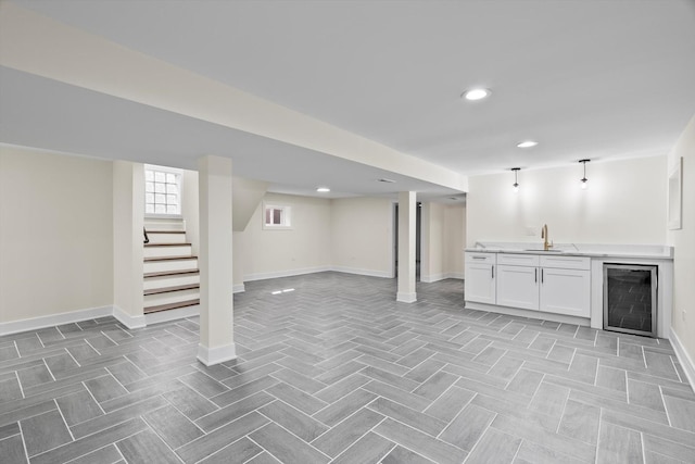 below grade area with baseboards, a sink, stairs, indoor wet bar, and wine cooler