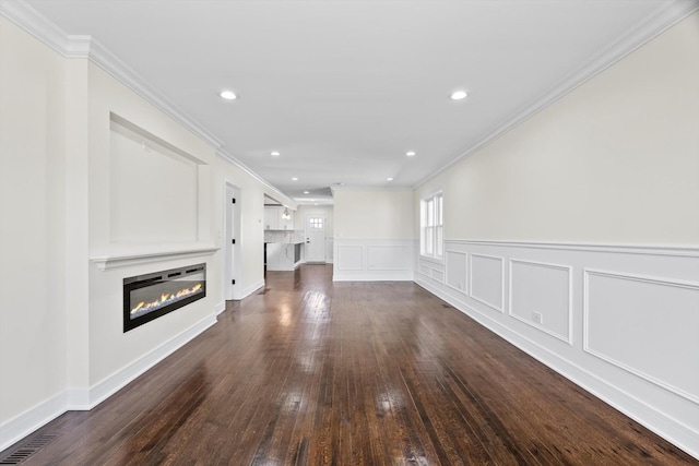 unfurnished living room featuring recessed lighting, a glass covered fireplace, dark wood-style flooring, and crown molding