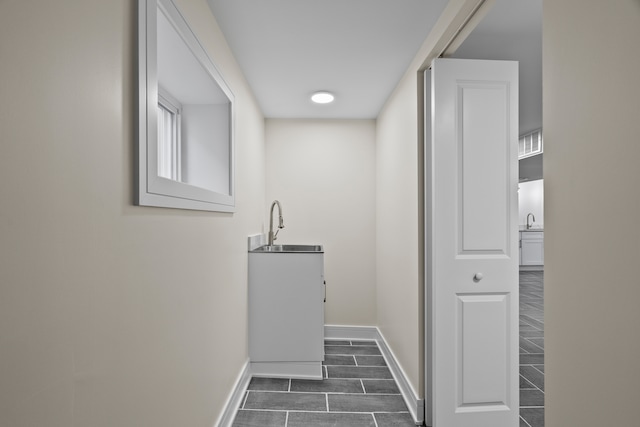 corridor featuring wood tiled floor, baseboards, and a sink