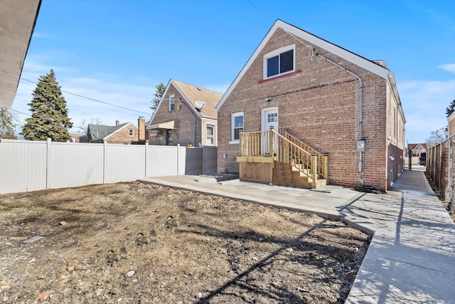 back of property with brick siding, a patio, and fence