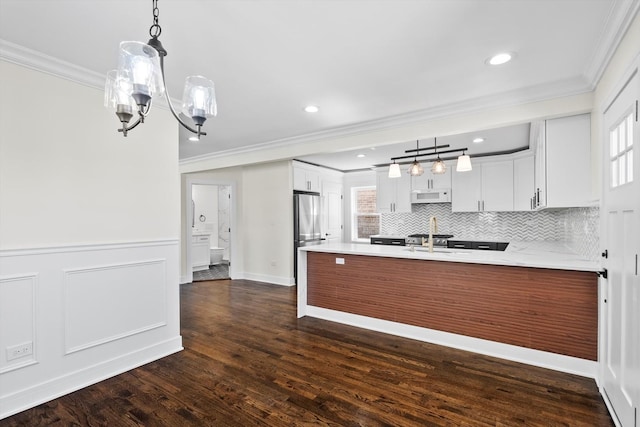 kitchen with white microwave, a peninsula, and crown molding