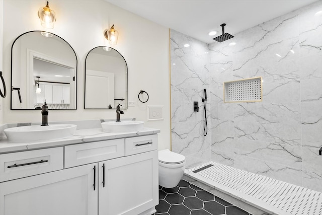 full bath with double vanity, toilet, a marble finish shower, and a sink