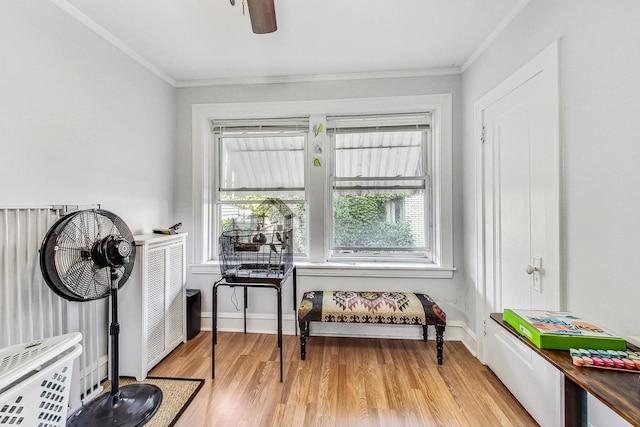 sitting room featuring light wood-style flooring, baseboards, and ornamental molding