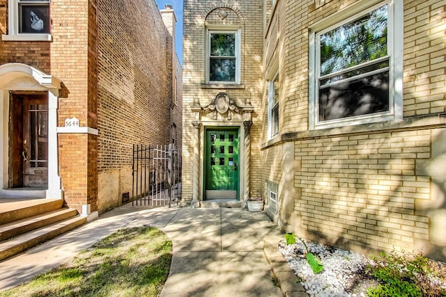 view of exterior entry featuring a gate and brick siding