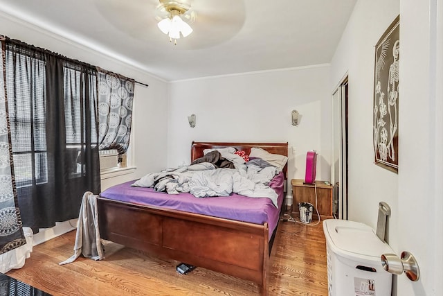 bedroom with ceiling fan, a closet, wood finished floors, and crown molding