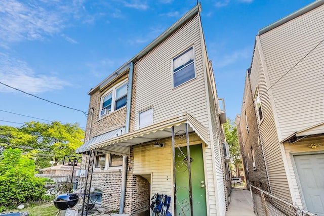 back of house featuring fence and brick siding