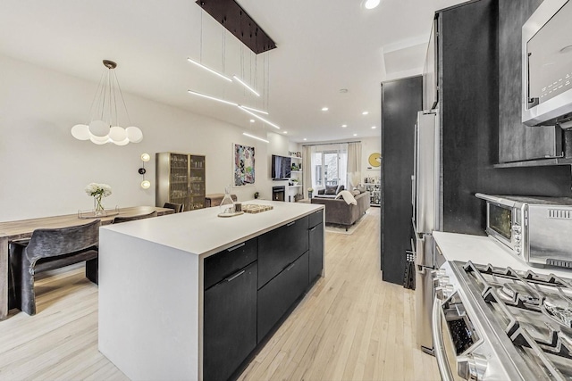 kitchen featuring a center island, stainless steel appliances, dark cabinetry, and light countertops