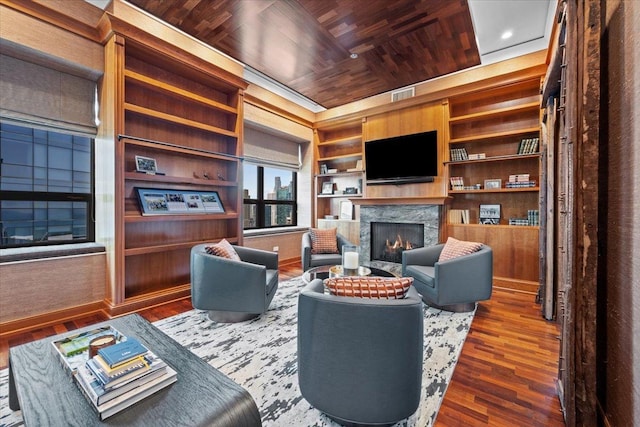 living room with visible vents, built in shelves, a warm lit fireplace, wooden ceiling, and wood finished floors