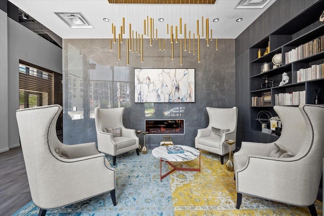 sitting room with a glass covered fireplace, wood finished floors, and visible vents