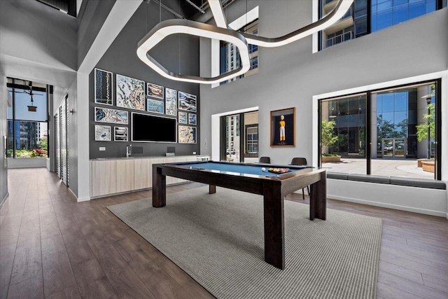 rec room featuring wood-type flooring, a towering ceiling, and billiards