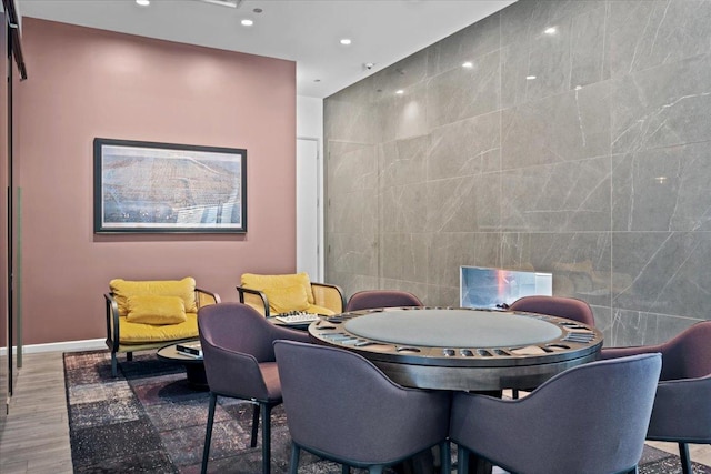 dining room featuring recessed lighting, baseboards, tile walls, and wood finished floors