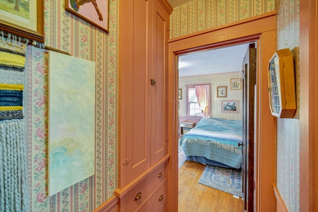 hallway with light wood-style flooring and wallpapered walls