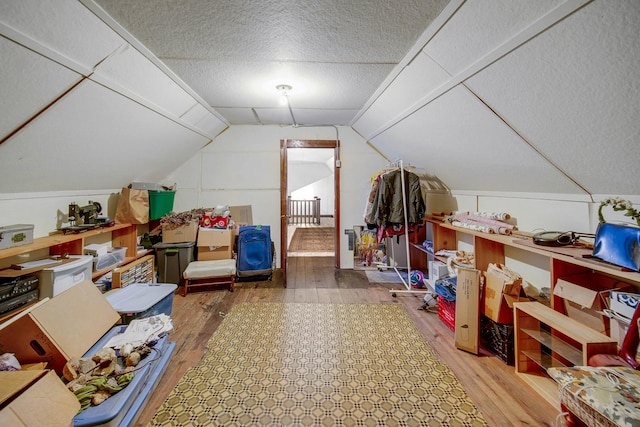 additional living space featuring lofted ceiling, a textured ceiling, and wood finished floors