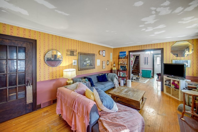 living area with visible vents, wood-type flooring, ornamental molding, and wallpapered walls