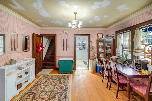 dining room with stairway, light wood-style floors, an inviting chandelier, crown molding, and wallpapered walls