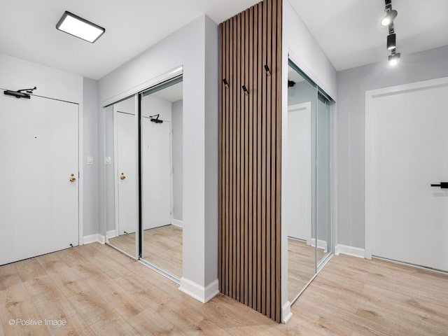 hallway with track lighting, baseboards, and wood finished floors