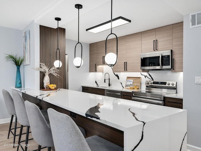 kitchen with visible vents, a breakfast bar, light countertops, appliances with stainless steel finishes, and light wood-type flooring