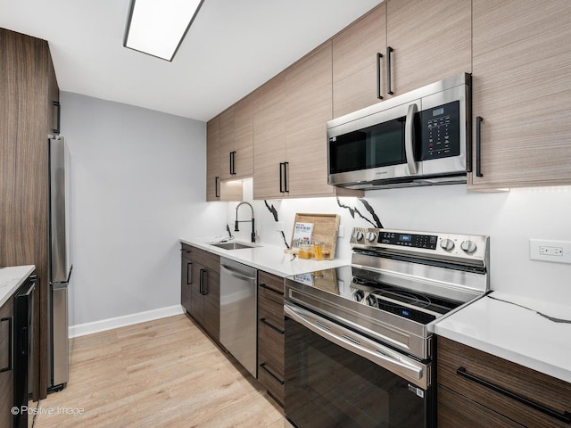 kitchen featuring a sink, light wood-style floors, appliances with stainless steel finishes, and light countertops