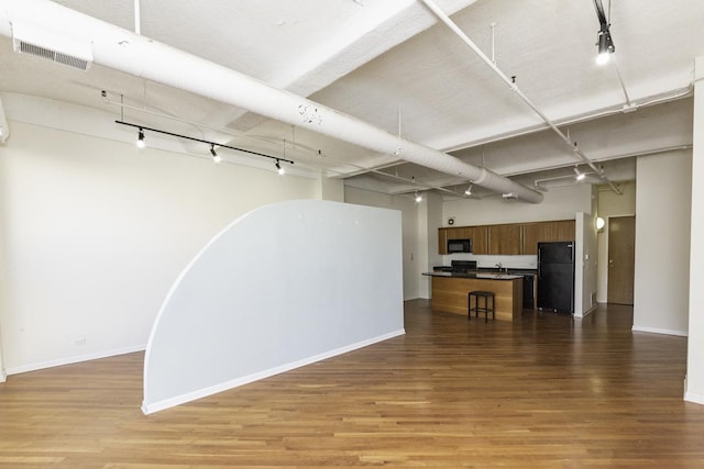 interior space featuring wood finished floors, visible vents, baseboards, freestanding refrigerator, and track lighting