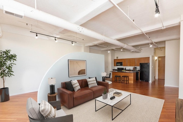 living area featuring track lighting, light wood-style floors, and baseboards