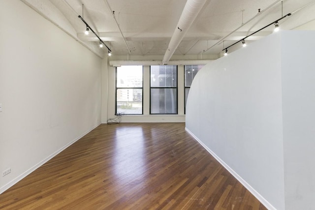 spare room with track lighting and wood finished floors