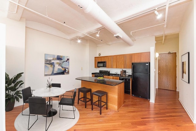 kitchen with black appliances, rail lighting, brown cabinets, and a center island