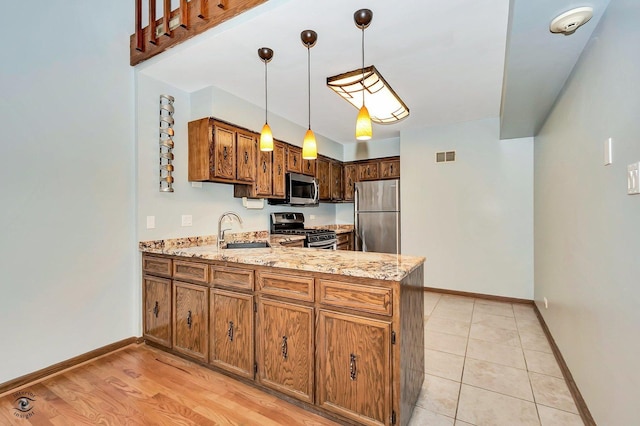 kitchen featuring visible vents, light stone countertops, appliances with stainless steel finishes, a peninsula, and a sink