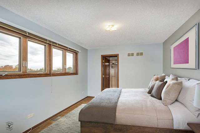 bedroom featuring visible vents, a textured ceiling, and baseboards