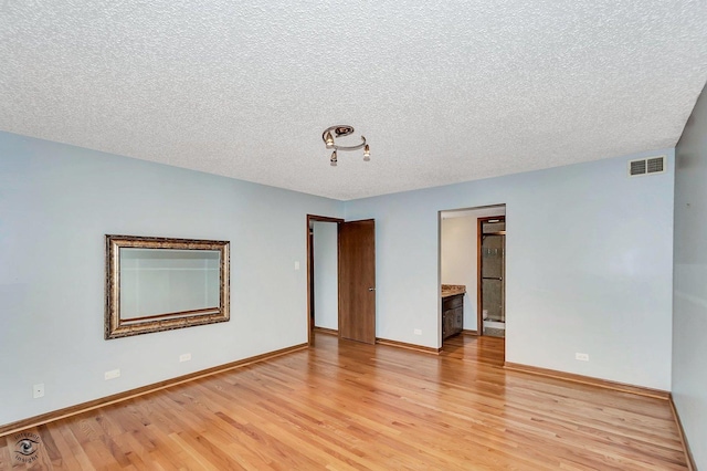 spare room with visible vents, baseboards, a textured ceiling, and light wood-style flooring