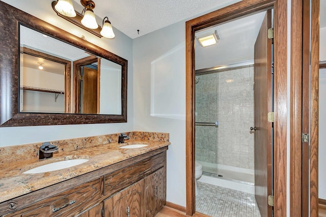 full bathroom featuring a sink, a textured ceiling, a stall shower, and toilet