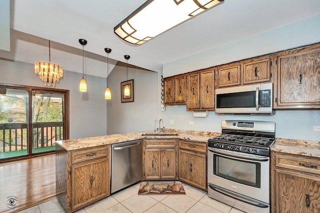 kitchen featuring brown cabinetry, a peninsula, stainless steel appliances, and a sink